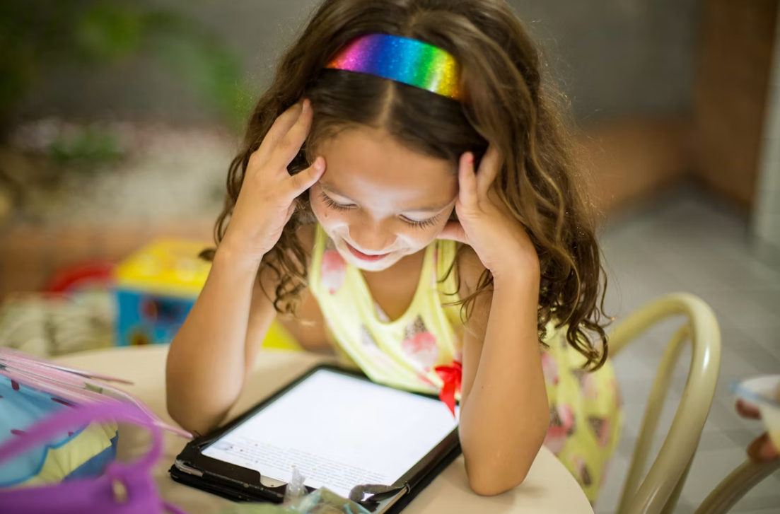 A young girl smiling while using the Colo Learn app on a phone